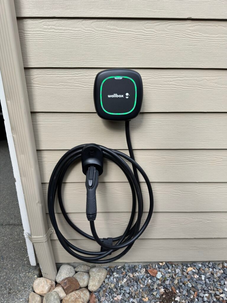 Wallbox EV charger mounted outdoors with the charging cable stored below